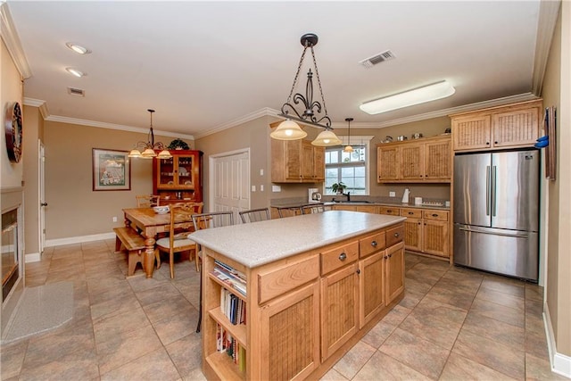 kitchen featuring pendant lighting, sink, stainless steel fridge, and a kitchen island