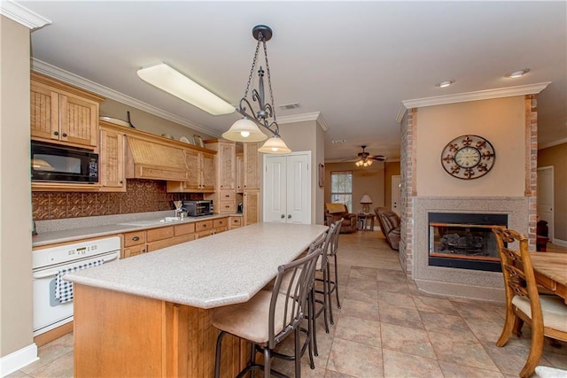 kitchen featuring a multi sided fireplace, black microwave, decorative backsplash, hanging light fixtures, and white oven