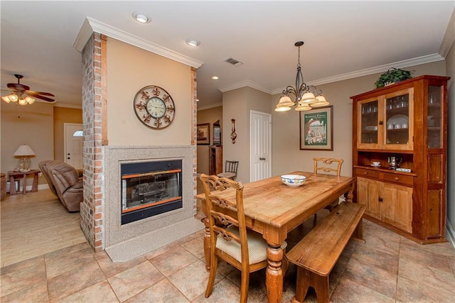 dining space with crown molding, a brick fireplace, and ceiling fan with notable chandelier