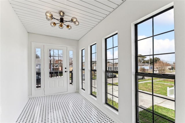 unfurnished sunroom featuring an inviting chandelier and a healthy amount of sunlight