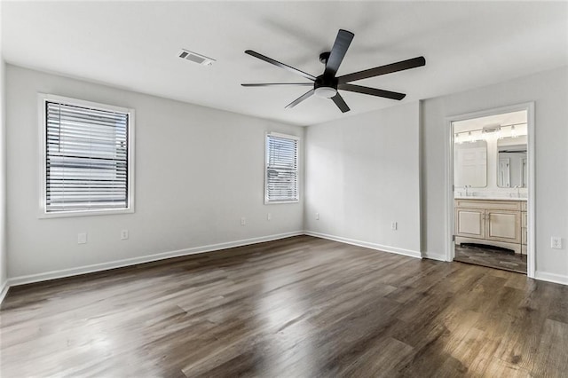 unfurnished bedroom with ensuite bath, dark wood-type flooring, and ceiling fan