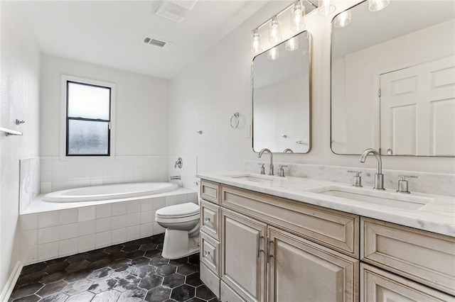 bathroom featuring vanity, tiled bath, and toilet