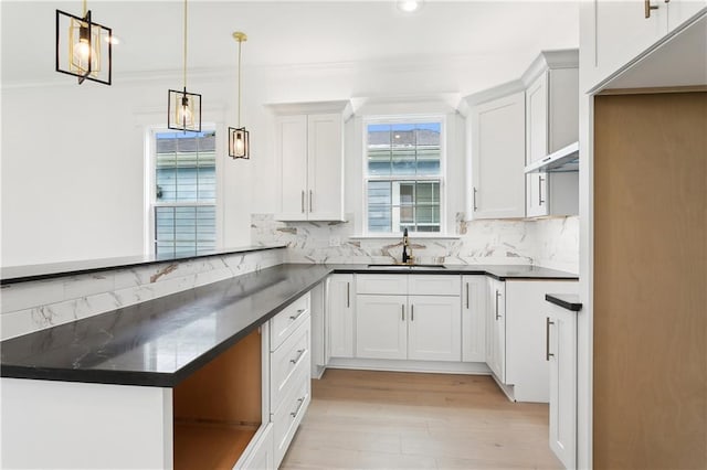 kitchen featuring tasteful backsplash, crown molding, white cabinets, and decorative light fixtures