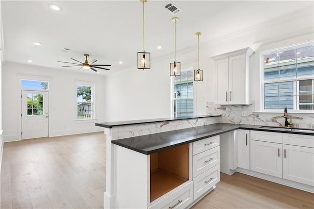 kitchen with white cabinetry, sink, hanging light fixtures, and light wood-type flooring