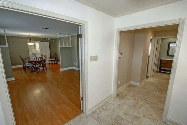 hallway with ornamental molding and light hardwood / wood-style floors