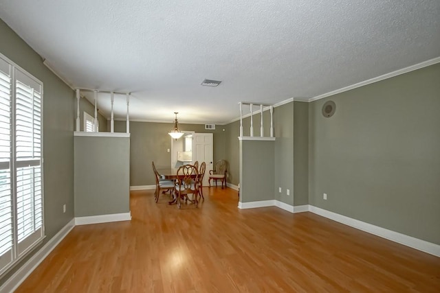 unfurnished dining area with wood-type flooring, ornamental molding, and a textured ceiling