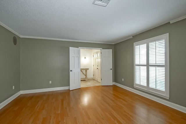 unfurnished room featuring ornamental molding, a textured ceiling, and light wood-type flooring