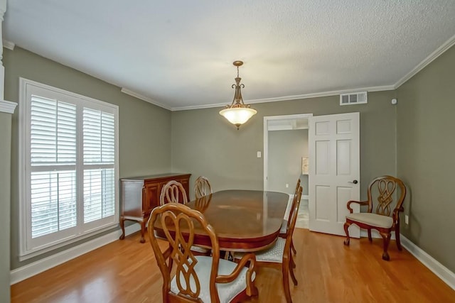 dining room with ornamental molding, a textured ceiling, and light wood-type flooring