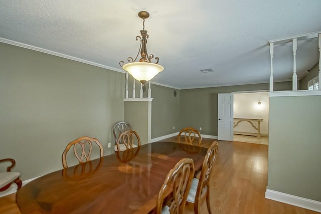 dining area featuring wood-type flooring, a textured ceiling, and crown molding