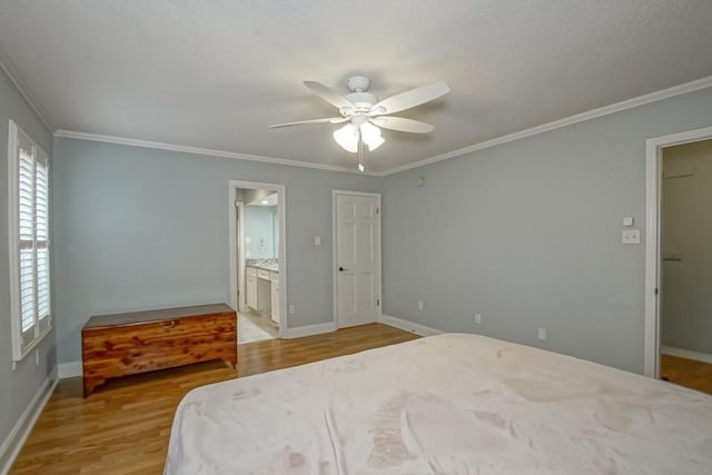 bedroom with crown molding, ensuite bathroom, ceiling fan, and light wood-type flooring