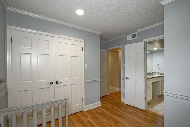 bedroom with a closet, ornamental molding, a textured ceiling, and light hardwood / wood-style flooring