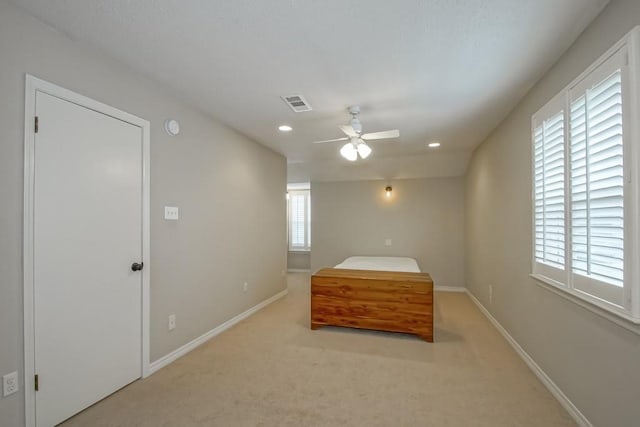 unfurnished bedroom with ceiling fan, light colored carpet, and multiple windows