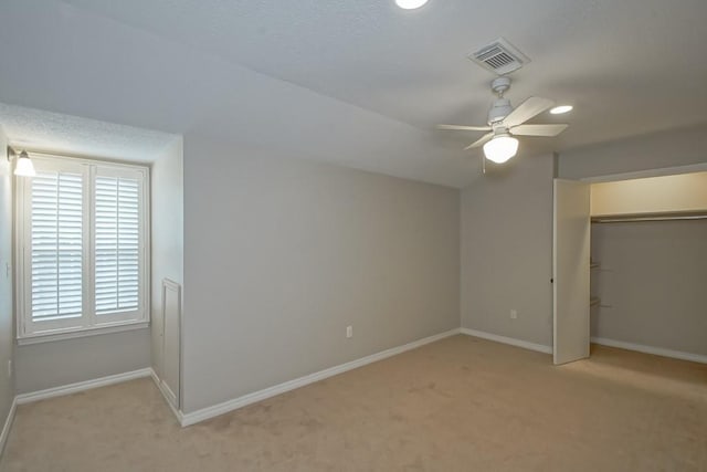 unfurnished bedroom featuring light colored carpet, a closet, and ceiling fan