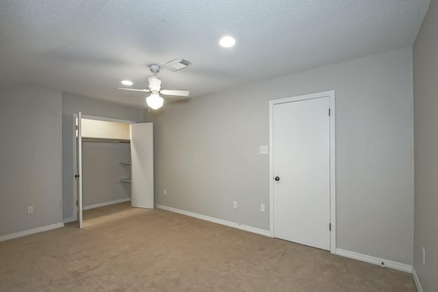 unfurnished bedroom with ceiling fan, light carpet, and a textured ceiling