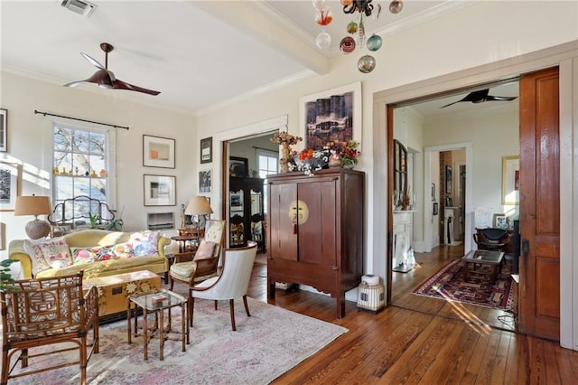 living area featuring ornamental molding, dark wood-type flooring, and ceiling fan