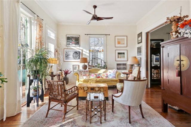 living area featuring hardwood / wood-style floors, ornamental molding, and ceiling fan