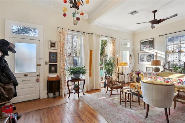 living area featuring crown molding, ceiling fan, wood-type flooring, and a wealth of natural light