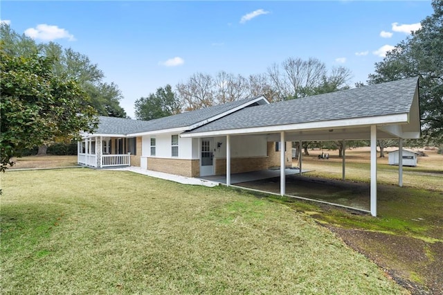 exterior space with an attached carport, roof with shingles, a yard, a porch, and brick siding