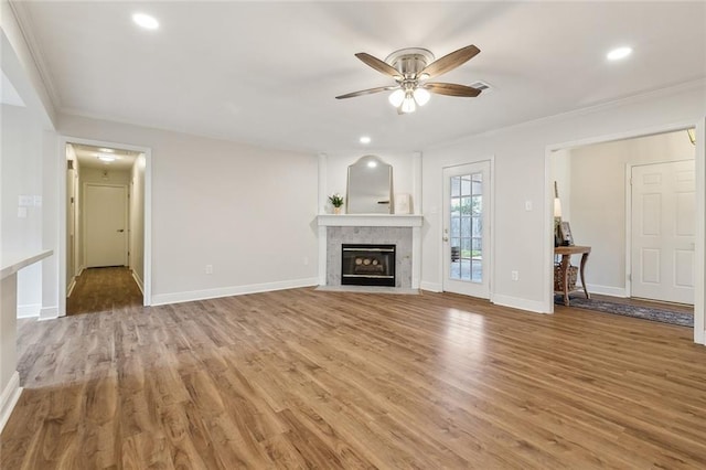 unfurnished living room with ornamental molding, ceiling fan, a fireplace, and light hardwood / wood-style floors