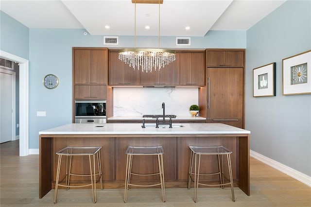 kitchen featuring pendant lighting, sink, an island with sink, and a kitchen bar