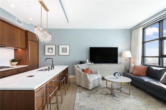 living room featuring sink, an inviting chandelier, and light hardwood / wood-style floors