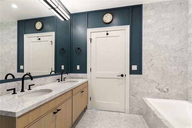 bathroom featuring vanity, a relaxing tiled tub, and tile walls