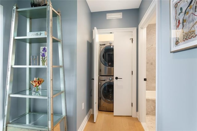 washroom with light wood-type flooring and stacked washer / dryer