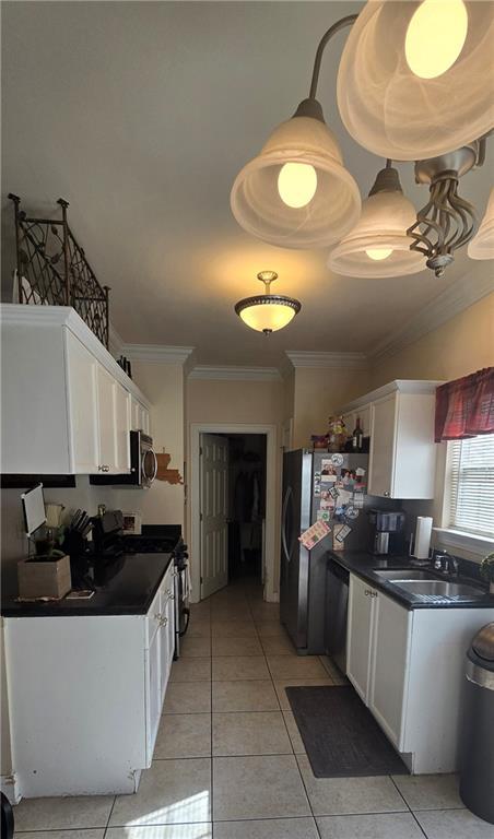 kitchen featuring light tile patterned flooring, sink, white cabinetry, ornamental molding, and appliances with stainless steel finishes