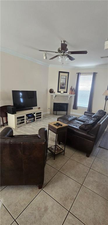 living room with crown molding, ceiling fan, and light tile patterned floors