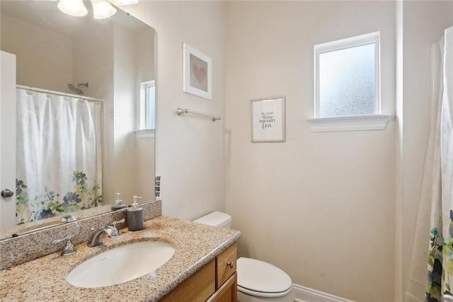 bathroom with vanity, plenty of natural light, walk in shower, and toilet