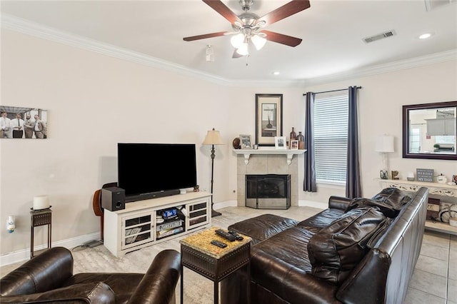 tiled living room featuring a tile fireplace, ornamental molding, and ceiling fan