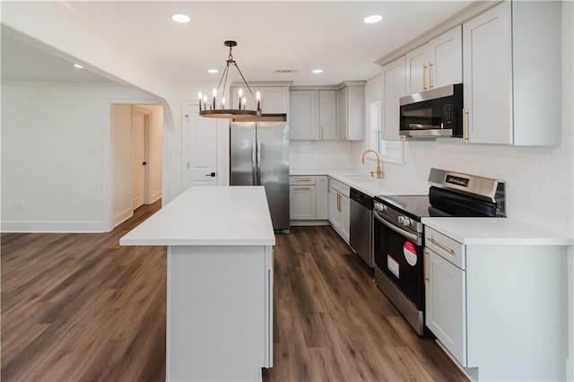 kitchen with sink, stainless steel appliances, a center island, tasteful backsplash, and decorative light fixtures