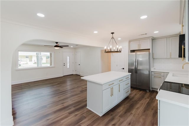 kitchen with stainless steel refrigerator, hanging light fixtures, backsplash, dark hardwood / wood-style floors, and a center island