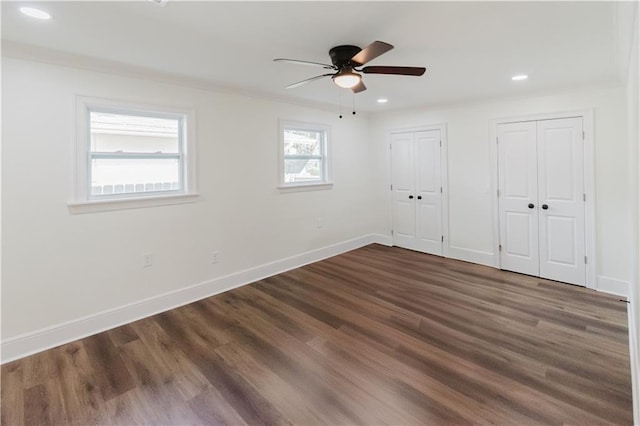 unfurnished bedroom with multiple closets, ceiling fan, and dark wood-type flooring