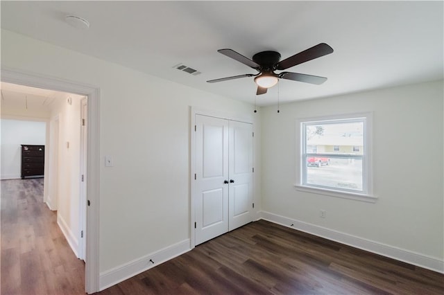 unfurnished bedroom featuring ceiling fan, dark hardwood / wood-style flooring, and a closet