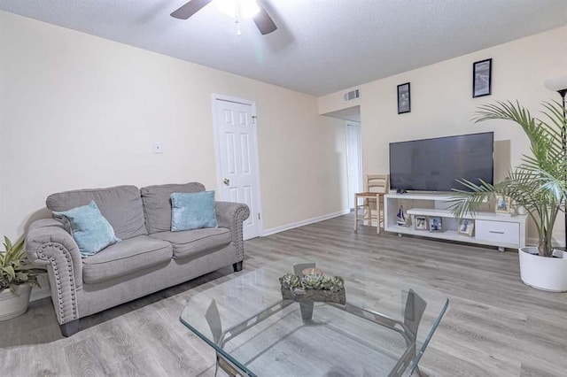 living room with ceiling fan, hardwood / wood-style floors, and a textured ceiling