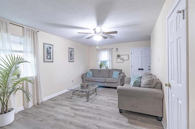 living room featuring ceiling fan, light hardwood / wood-style flooring, and a textured ceiling