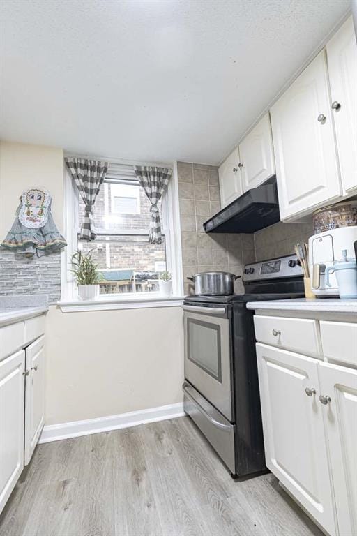 kitchen with exhaust hood, stainless steel electric range, light wood-type flooring, decorative backsplash, and white cabinets