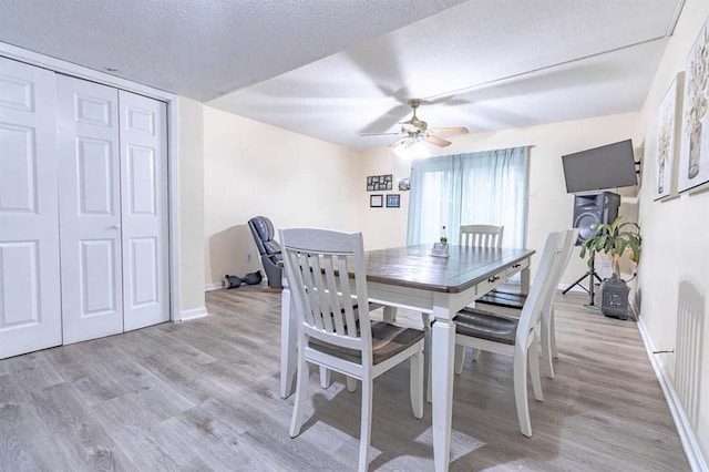 dining space featuring ceiling fan, light hardwood / wood-style flooring, and a textured ceiling