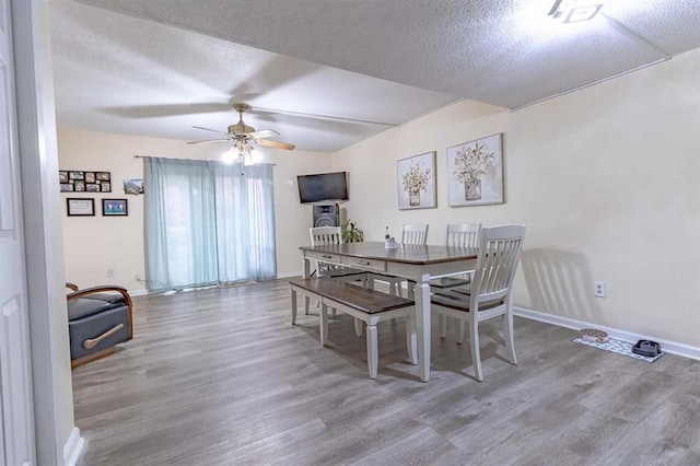 dining space with ceiling fan, a textured ceiling, and light wood-type flooring