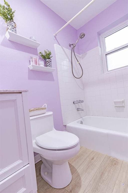 bathroom with tiled shower / bath combo and toilet