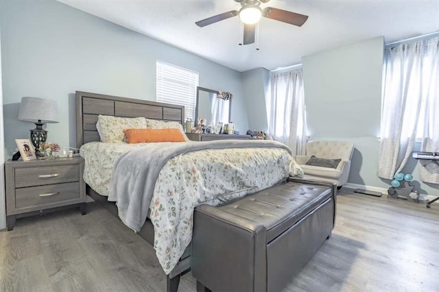 bedroom with multiple windows, wood-type flooring, and ceiling fan