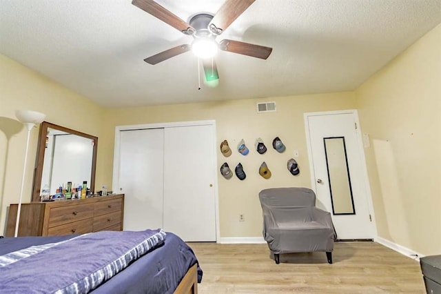 bedroom featuring a textured ceiling, light hardwood / wood-style flooring, a closet, and ceiling fan