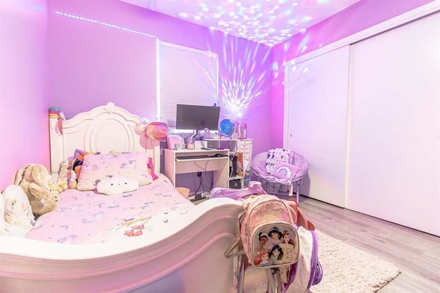 bedroom with light hardwood / wood-style floors and a closet