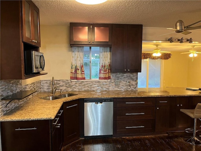 kitchen with sink, dark wood-type flooring, appliances with stainless steel finishes, decorative backsplash, and kitchen peninsula