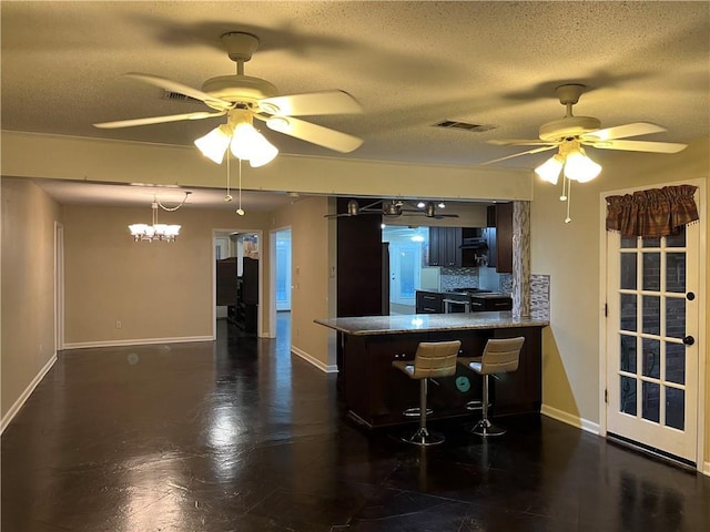 kitchen featuring ceiling fan, stainless steel range, kitchen peninsula, and a textured ceiling