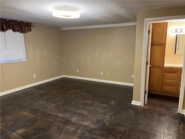 empty room featuring ornamental molding and a textured ceiling