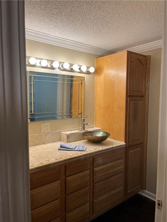 bathroom featuring ornamental molding, vanity, and a textured ceiling