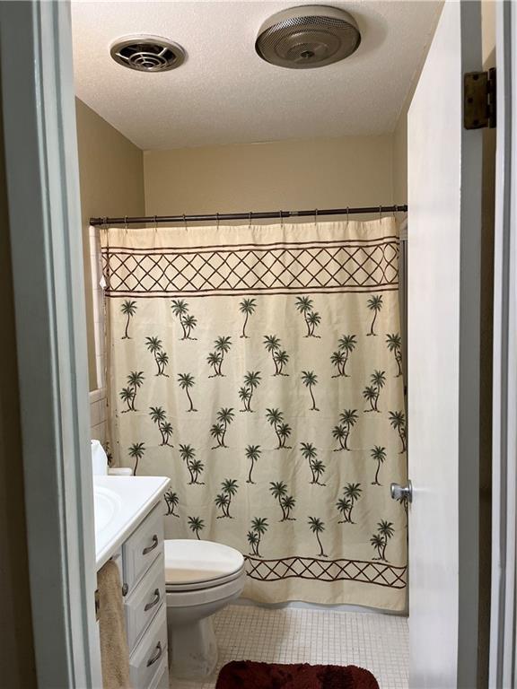 bathroom with tile patterned floors, vanity, toilet, and a textured ceiling