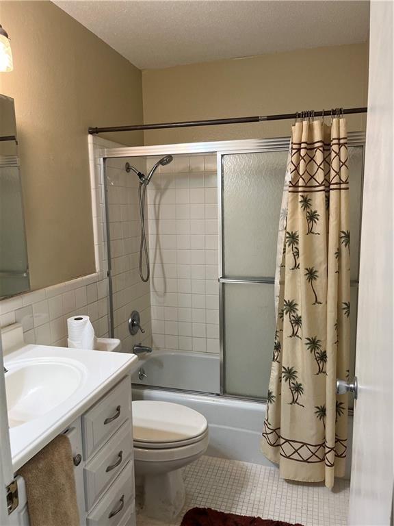 full bathroom with tile walls, tile patterned flooring, vanity, toilet, and shower / bath combo